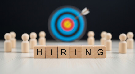 Hiring concept with wooden blocks spelling hiring surrounded by wooden figures and a target with an arrow representing recruitment talent acquisition and achieving business goals and objectives