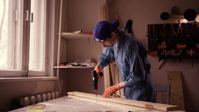 Young male Carpenter working with drill at carpentry workshop - Powered by Adobe