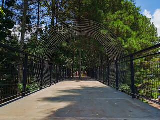 Modern park bridge and stone stairs with metal mesh railings
