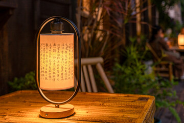 Traditional Chinese lamp with text on wooden table in outdoor setting