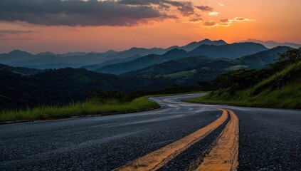 Asphalt road curves through mountain range during a vibrant sunset