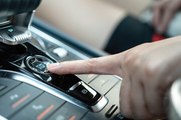 Fototapeta premium Action of a car driver's finger is pressing on engine start button of the modern sport car. Close-up with selective focus.