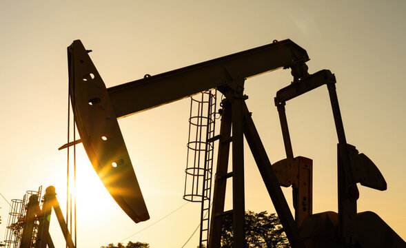 Beam pump or Donkey pump operating to recovered crude oil from the production oil well, Photo in silhouette shadow. Industrial with technology scene.