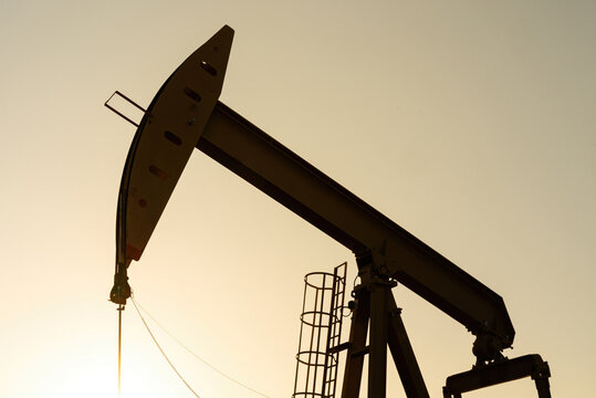 Beam pump or Donkey pump operating to recovered crude oil from the production oil well, Photo in silhouette shadow. Industrial with technology scene.