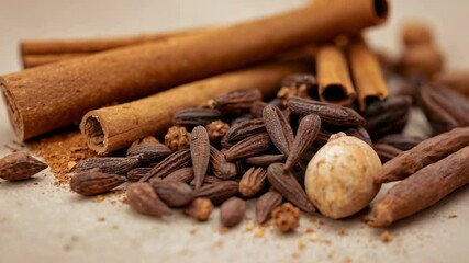 Pulling back camera, racking focus to reveal pile of spices on table with cinnamon, clove buds - Powered by Adobe