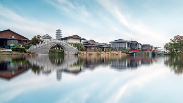 Traditional Chinese architecture with a stone bridge and calm water - Powered by Adobe