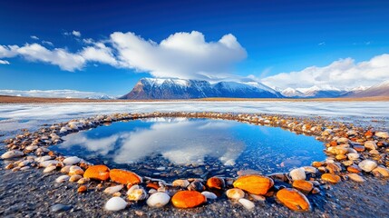 A beautiful landscape featuring a reflecting pool surrounded by colorful stones, with snow-capped mountains in the background under a bright blue sky with fluff