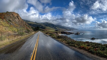 A wet asphalt road stretches along a coast between cliffs and the vast ocean beneath a cloudy sky