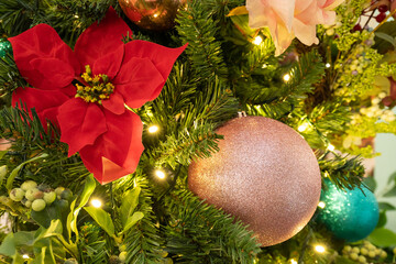 A lush Christmas tree adorned with poinsettia blooms, glittering ornaments, and twinkling lights...