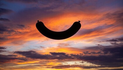 Pixelated banana shape silhouette floating against a dramatic sunset sky with vibrant orange and purple clouds