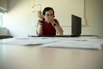 Exhausted Teacher Grading Student Papers at Her Desk, Overwhelmed Educator With Stack of Homework to Grade