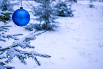 New Year's blue ball on the background of snow covered fir trees