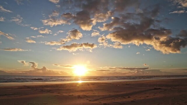 Spectacular Andalusian sunset over the Atlantic Ocean at Cuesta Maneli beach. Golden hour light, dramatic clouds, sandy shore, tranquil sea, and beautiful nature travel landscape.