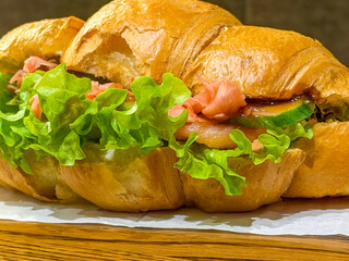 fresh croissant sandwich red fish teriyaki sauce close up delicious pastry on wooden board gourmet seafood meal concept of bakery, restaurant, healthy eating