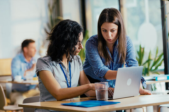 Two Female Startup Team Members Preparing Pitch Presentation Notes at Conference Venue Cafe