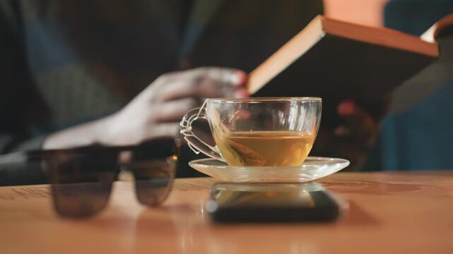 calm moment with beverage and literature, serene environment for relaxing with warm drink and reading material, soothing ambiance where one can unwind with cup of coffee and engaging literature