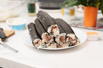 Homemade tuna sushi rolls on a white plate ready to serve during a casual lunch in the kitchen