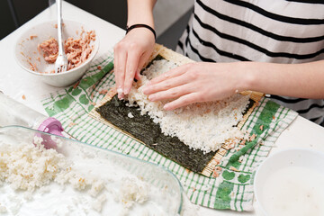 Preparing homemade Tuna sushi in the Kitchen, spreading Rice on Nori sheet, making Lunch and enjoying the Culinary art