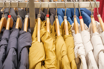 Winter down jackets hanging on hangers in the store close-up, side view.