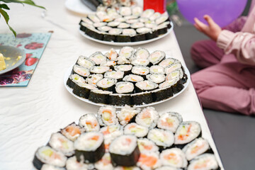 Sushi feast prepared for a Birthday party, showcasing plates filled with California rolls and other nori rolls