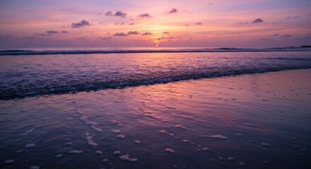 Fototapeta premium Vibrant sunset over a tranquil beach. Gentle waves lap at the shore, reflecting the fiery hues of the sky