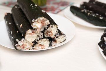 Homemade Gimbap Rolls Stacked High on White Plates, Waiting to be Served on a Bright Afternoon
