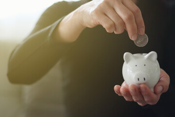 asian women putting coin in white piggy bank ,  for the business and money concept
