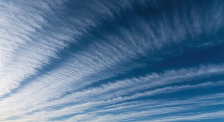 Wispy, layered clouds fill a vast, vibrant blue sky