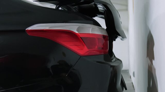 Close-up of a modern black car's trunk automatically opening in a parking garage