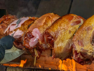 large roasted pork knuckle ham on a spit over open fire close up traditional czech slovak new year's fair food preparation concept of street food, traditional cuisine, christmas market