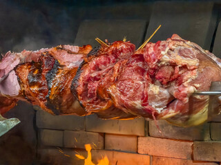 large roasted pork knuckle ham on a spit over open fire close up traditional czech slovak new year's fair food preparation concept of street food, traditional cuisine, christmas market