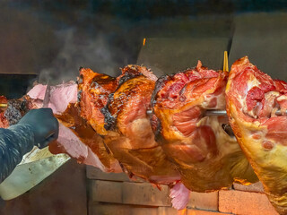 large roasted pork knuckle ham on a spit over open fire close up traditional czech slovak new year's fair food preparation concept of street food, traditional cuisine, christmas market