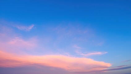 Fototapeta premium Pastel pink and orange clouds against deep blue sky at sunset or sunrise creating soft gradient atmospheric scene