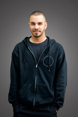 Portrait of a confident young man standing against grey wall