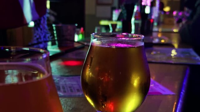 Nighttime urban pub ambiance featuring lone individual savoring beer under colorful magenta lighting