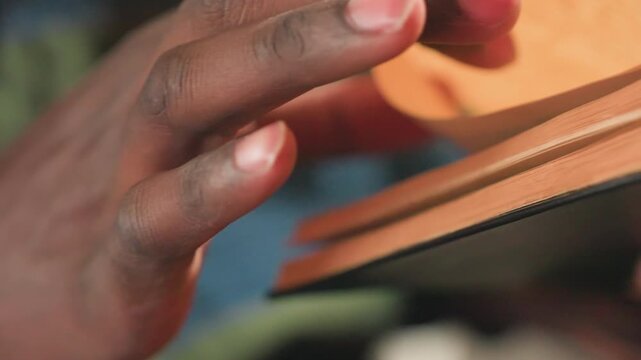 closeup black hands flipping pages, soft natural light, warm paper grain, thumb turning, reader pausing between chapters, student studying at desk, librarian cataloging, writer researching notes, poet