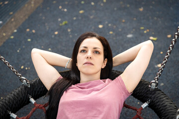 Close-up overhead portrait of a woman with her hands behind her head, lying and relaxing in a nest swing.