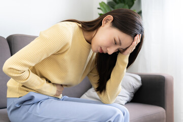 Asian women have stomach ache. Stomach ache due to eating irregularly, menstrual cramps,...