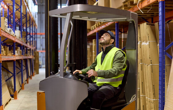 Warehouse forklift operator inspects racking for pallets. Worker checks shelves and aligns forks for loading and delivery and storage within logistics. Clear warehouse logistics concept today.