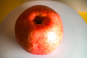 The apple on the white plate is cut in half with a knife