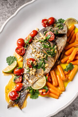 Whole baked fish with tomatoes herbs and carrots
