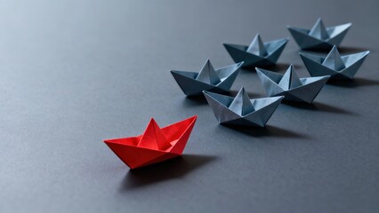 A red paper boat leads a group of blue paper boats on a dark surface, symbolizing leadership and direction.