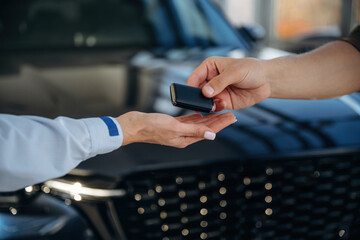Ownership conception. Close up view of woman's and man's hands that are taking the keys for new car