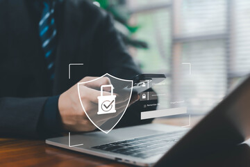 A business professional using a smartphone and laptop with a glowing digital security shield, representing secure login, cybersecurity, data protection, authentication, privacy, modern digital safety