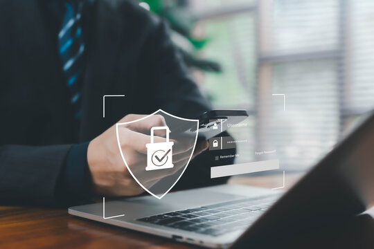 A business professional using a smartphone and laptop with a glowing digital security shield, representing secure login, cybersecurity, data protection, authentication, privacy, modern digital safety