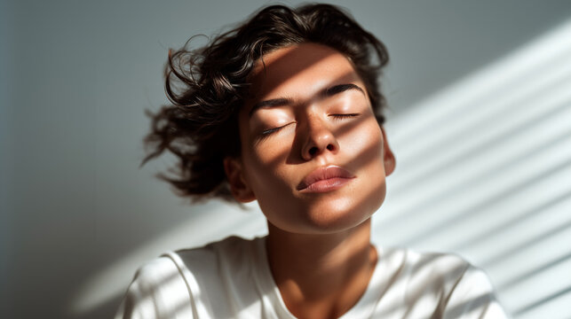 Woman meditating with eyes closed in natural sunlight and shadows. Mental health wellness and spiritual healing concept. Peaceful mindfulness and inner tranquility. Serene self-care and relaxation.