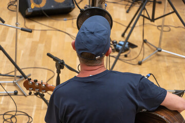Musician in recording studio playing acoustic guitar and singing into microphone