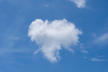 A bright white cloud naturally shaped like a heart floats against a clear blue sky