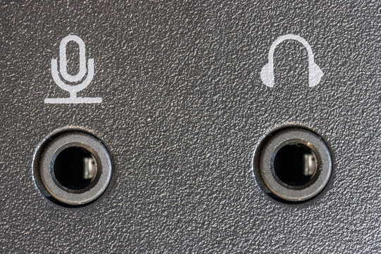 Close-up of two audio jacks - microphone and headphones set into a black textured panel.