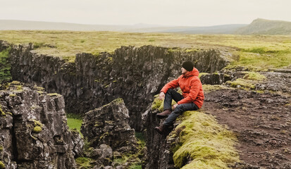 A man in a yellow jacket stands in Tingvelir National Park in Iceland. Fracture of tectonic plates. Panoramic photography